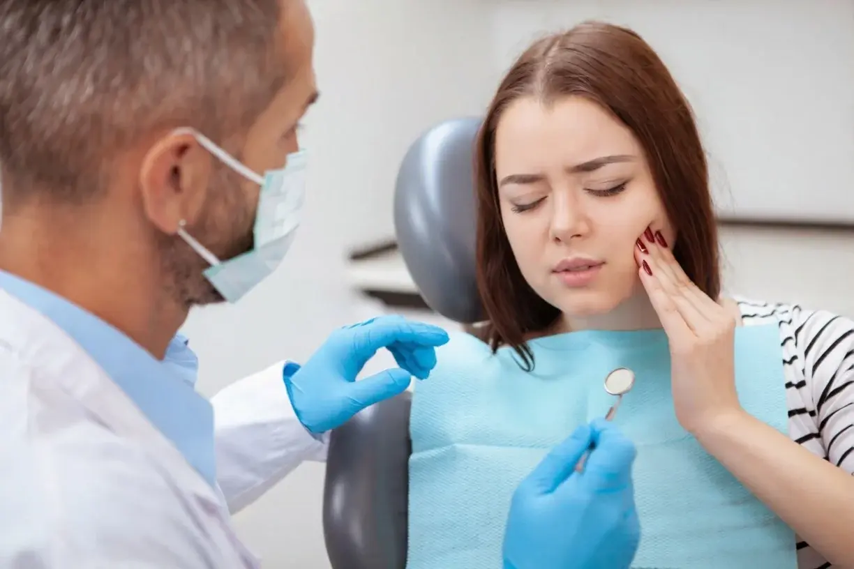 Woman experiencing jaw pain during a TMJ TMD dental treatment consultation with a dentist